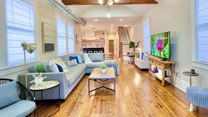 A spacious living room with a wooden ceiling, a large sectional sofa, a coffee table, and a television.