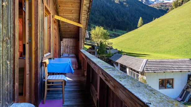 A wooden cabin with a balcony overlooking a mountainous landscape.
