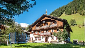 A wooden chalet with balconies, a ski lift, and a mountain backdrop.