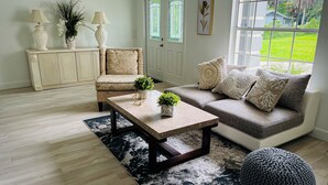 A living room with a sofa, a coffee table, a patterned armchair, and a decorative rug.