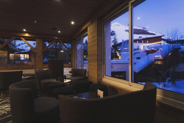 A cozy interior with large windows offering a view of a snowy mountain landscape.