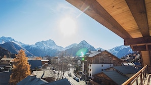 Ein Bergdorf mit Holzhäusern und Blick auf verschneite Berge.