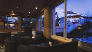 Ein gemütliches Interieur mit großen Fenstern, die einen Blick auf eine verschneite Berglandschaft bieten.