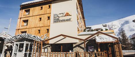 Un edificio de madera de varios pisos con un letrero que dice "BC7 Bar Restaurant" y "BASE CAMPLODGE".