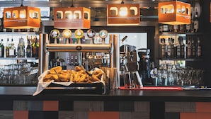 Zona de bar con pared a cuadros, techo de madera y diverso equipamiento.