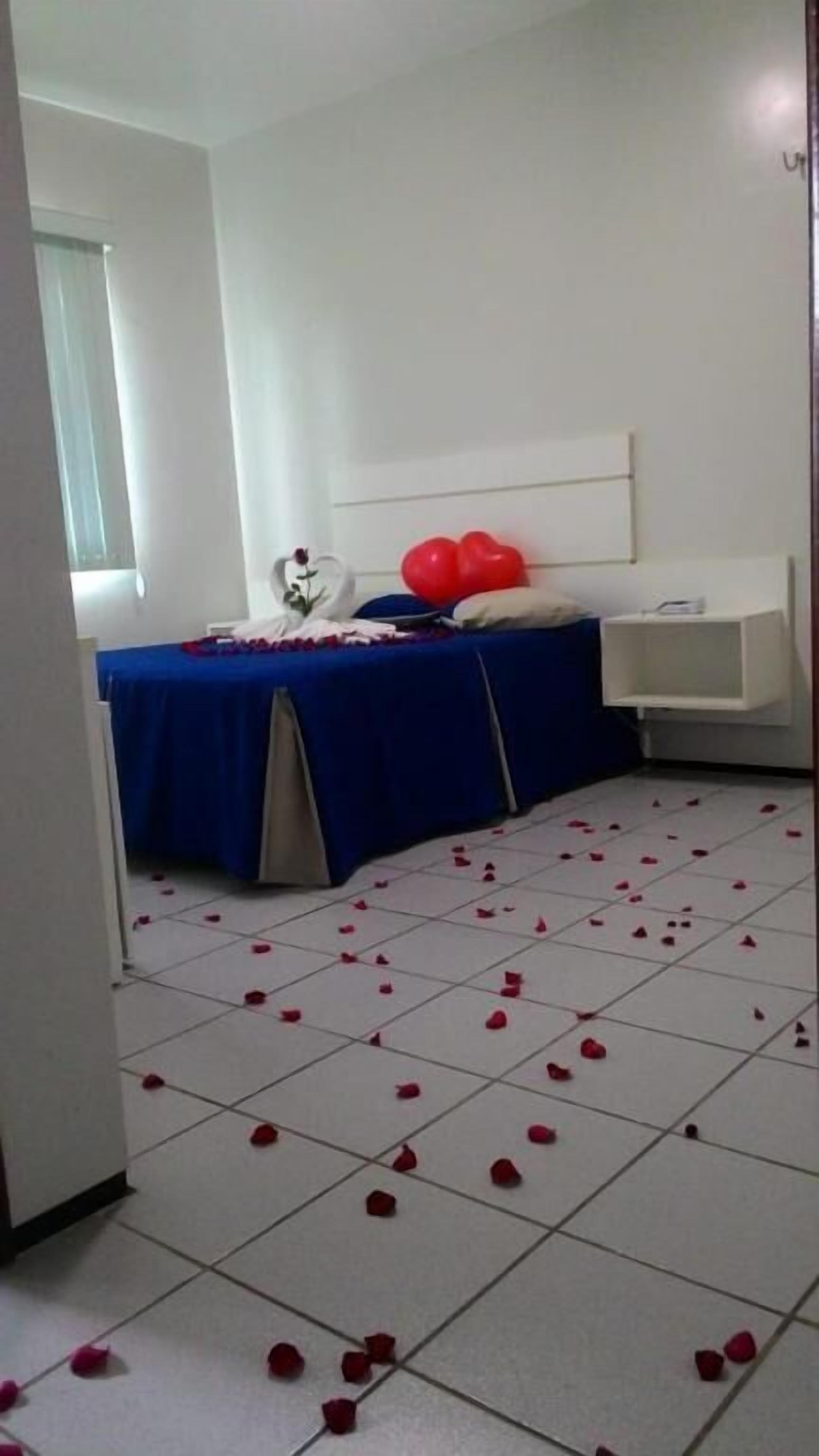 Quarto de hotel com uma cama, mesa de cabeceira e janela.