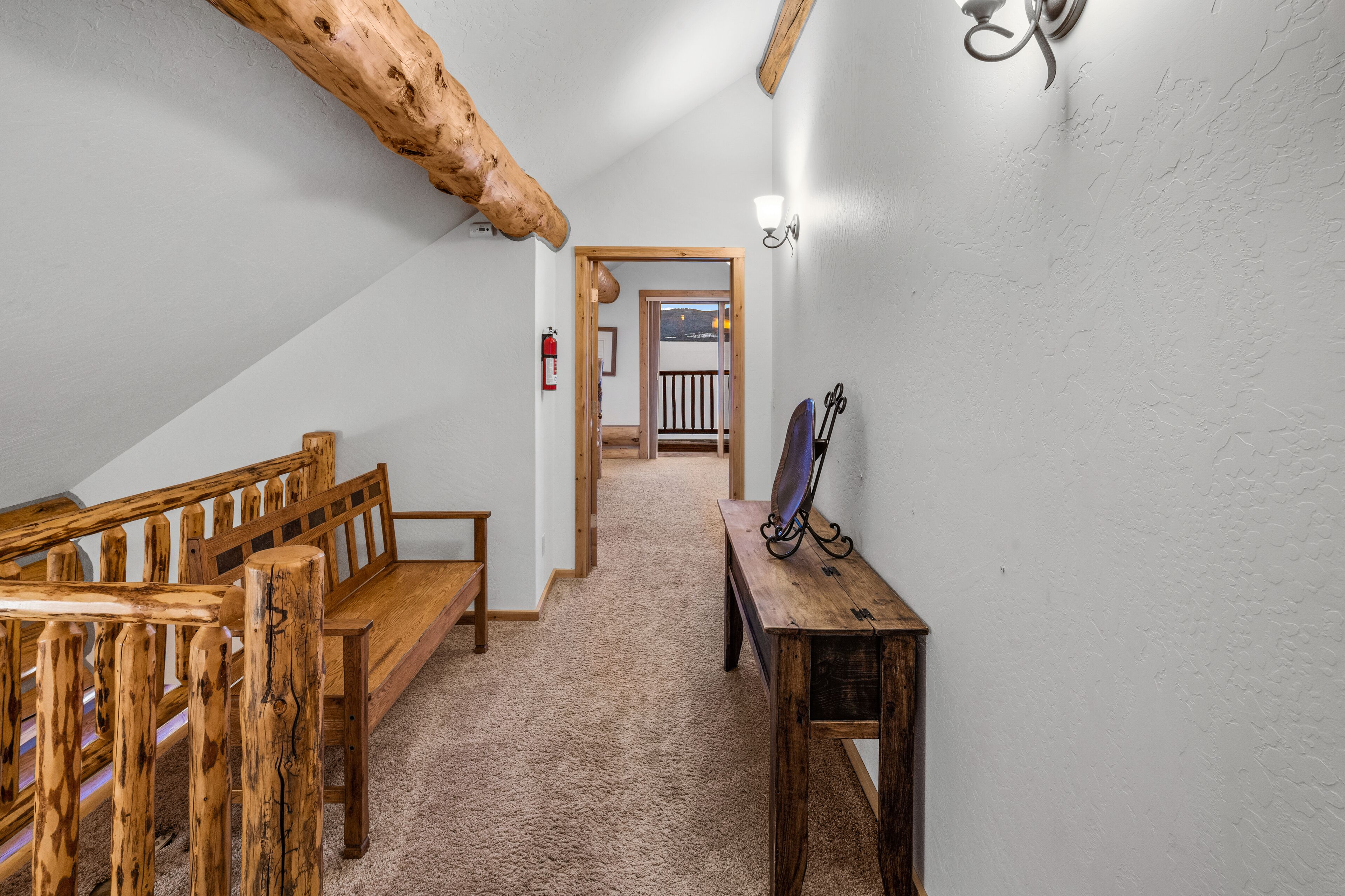 Un pasillo con bancos de madera, una mesa de madera y un accesorio de iluminación en la pared.