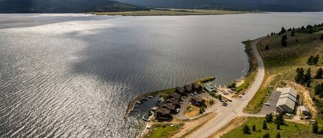 An aerial view of a lakeside property with a marina, several buildings, and a road leading to the water.