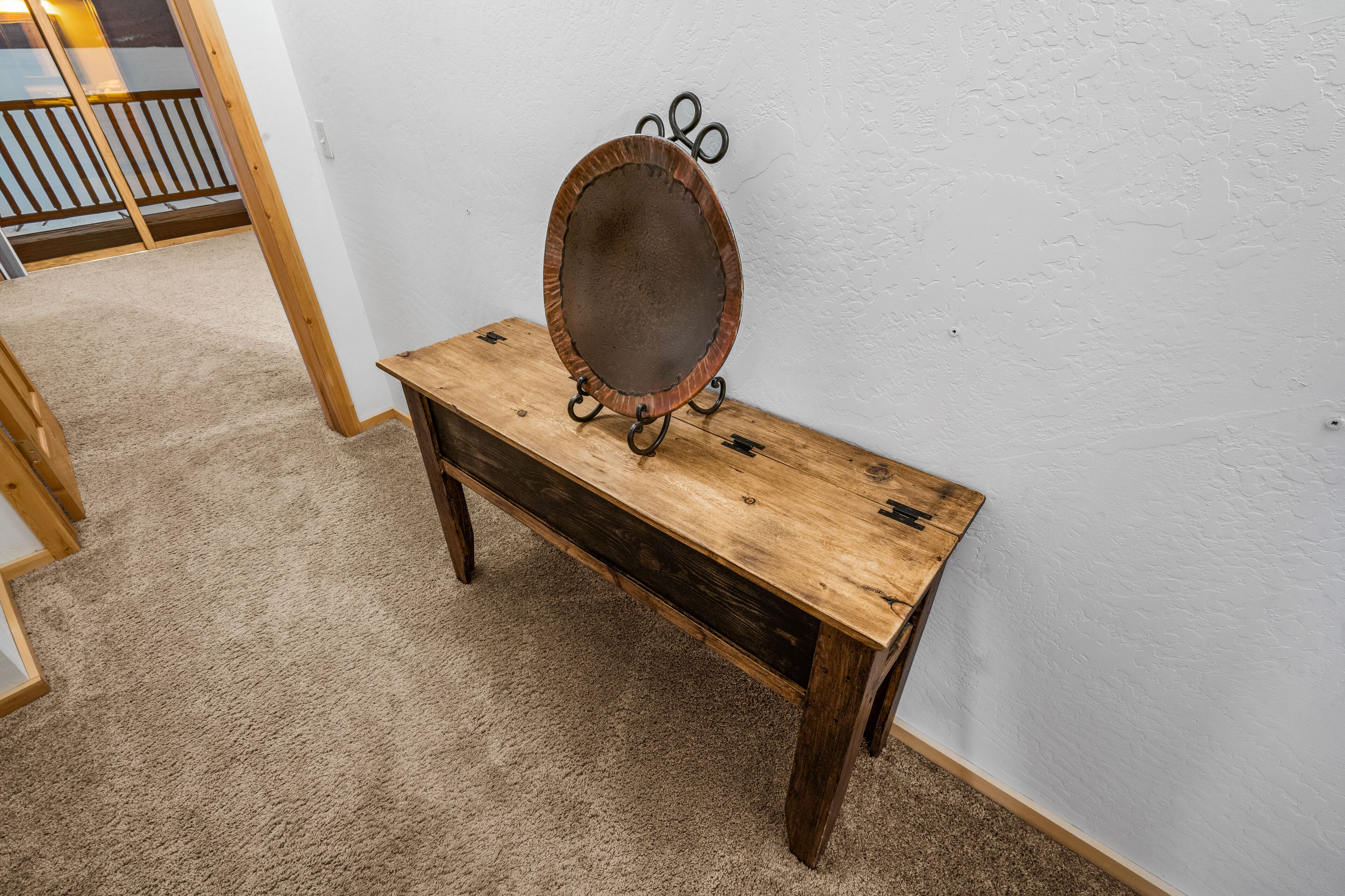 A wooden bench with a round mirror on top, against a plain wall.