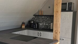 Cozinha moderna com painel de pedra atrás do fogão, micro-ondas embutido e bancada cinza.