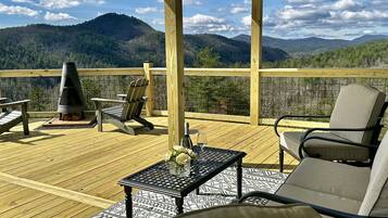 Une terrasse en bois avec des meubles d’extérieur, un barbecue et une vue imprenable sur les montagnes.