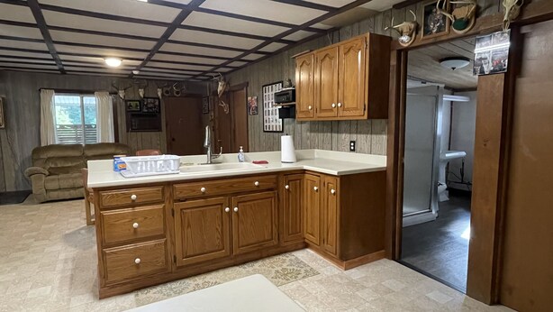 Una cocina con armarios de madera, encimera blanca y horno empotrado.