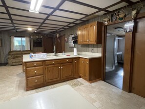 A kitchen with wooden cabinets, a white countertop, and a built-in oven. - Private family lodge on 42 serene acres- 15 minutes to Penn State- Centre County (Howard)