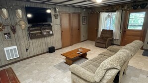 Una sala de estar con un sofá grande, una mesa de centro de madera, un televisor y una chimenea.