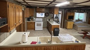 Una cocina compacta con armarios de madera, una estufa blanca y un lavamanos.
