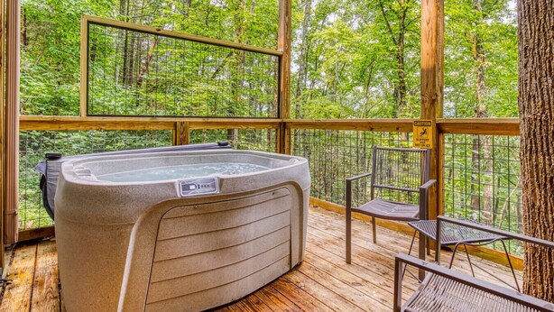 Ein Whirlpool auf einer Holzterrasse mit Blick auf einen Wald.