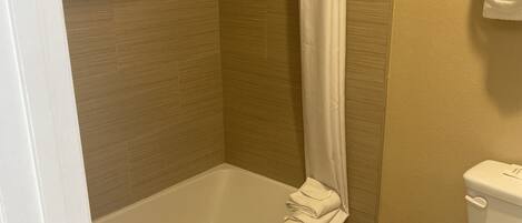 A bathroom with a bathtub, toilet, and a shower curtain.