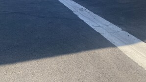 Um edifício com telhado de telhas vermelhas, uma escadaria e um estacionamento com um carro branco.