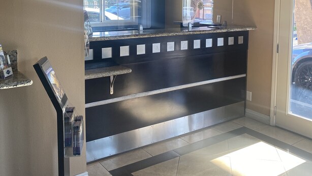 Cozinha moderna com bancada preta, eletrodomésticos de aço inoxidável, luminárias pendentes e vista pela janela.