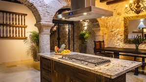 A kitchen with a stone archway, a central island with a gas stove, and a rustic wooden cabinet.