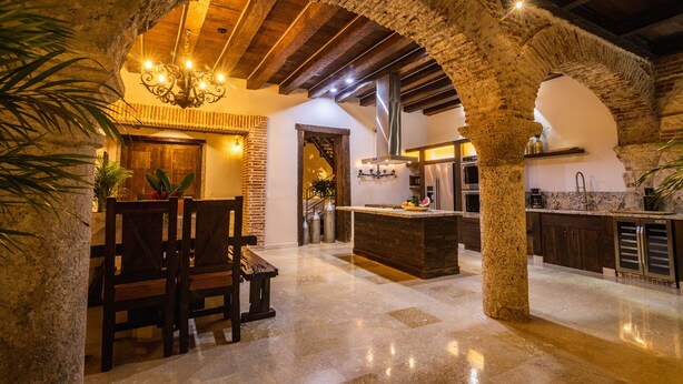 A spacious kitchen with a central island, stone arches, and a dining area with wooden furniture.