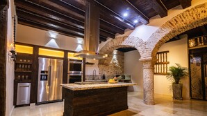 A kitchen with a central island, stainless steel appliances, and a stone archway.
