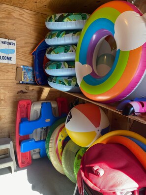 Zona de almacenamiento con varios juguetes inflables y equipo, incluyendo balones de playa y flotadores para piscina.