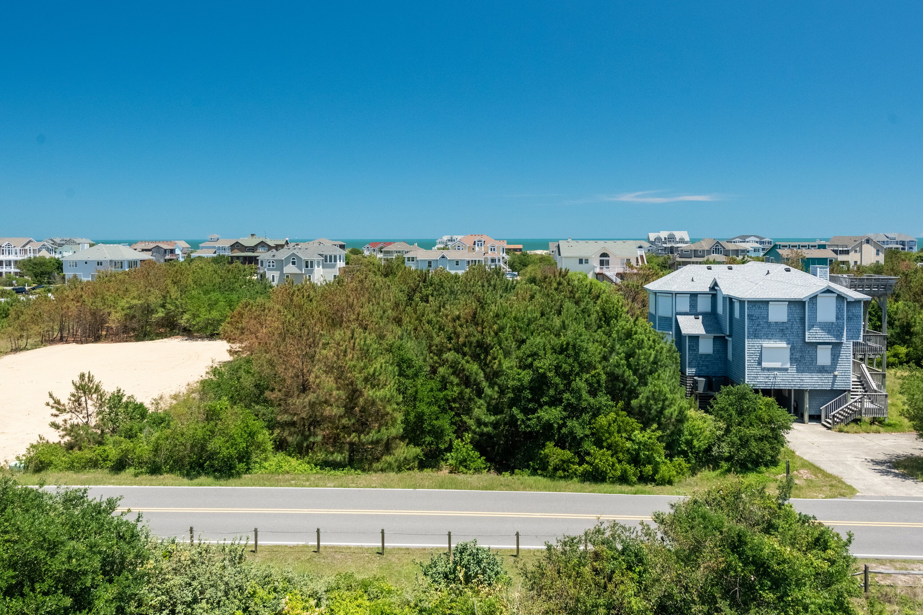 A coastal residential area with houses, a road, and a beach.