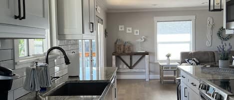 A modern kitchen with white cabinets, a marble countertop, and stainless steel appliances.
