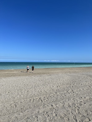 Una amplia playa de arena con huellas que se adentran en el agua.