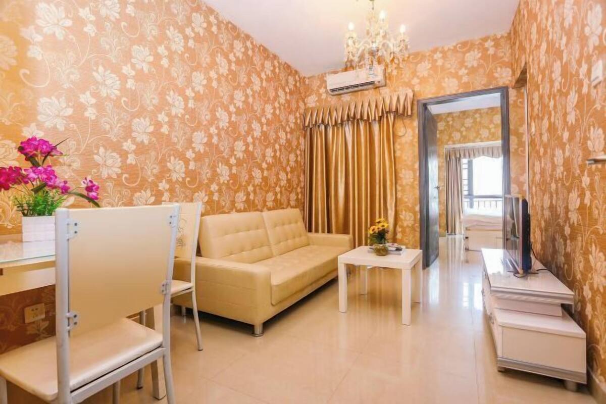 Una habitación con sofá, una silla, una mesita y televisor.