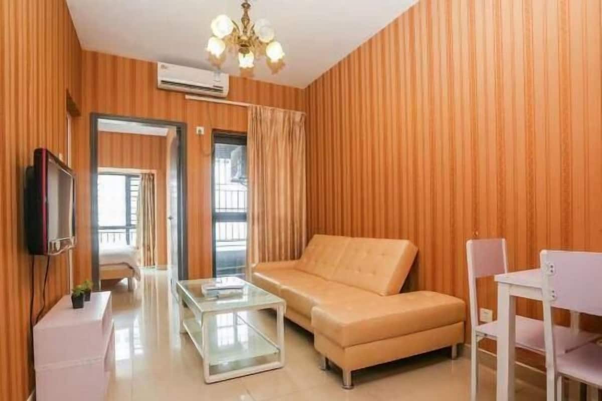 Una habitación con un sofá, una mesa de centro de vidrio, un televisor y una silla.