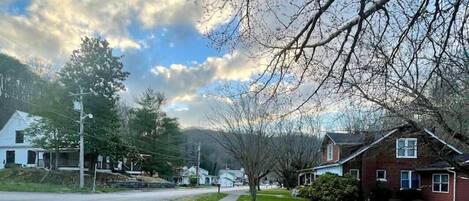 A suburban street with a sidewalk, houses, and trees.