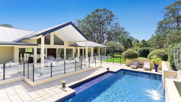 Une maison moderne dotée d’une grande piscine, d’un espace extérieur aménagé et d’un jardin bien entretenu.