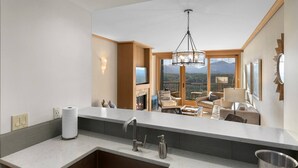 Eine moderne Küche mit einer großen Kochinsel, einem eingebauten Kamin und Blick auf einen Balkon mit Sitzgelegenheit.