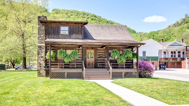A rustic wooden building with a porch, stone pillars, and potted plants.