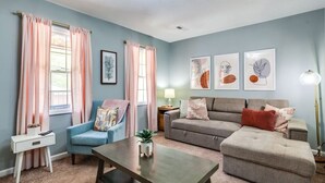 A living room with a blue armchair, a grey sofa, a wooden coffee table, and a floor lamp.
