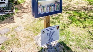 A small blue bookcase with a sign reading "Please enjoy on behalf of Lifeworks."