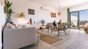 Un soggiorno moderno con divano, poltrone, tavolo da pranzo e un'ampia finestra con vista.