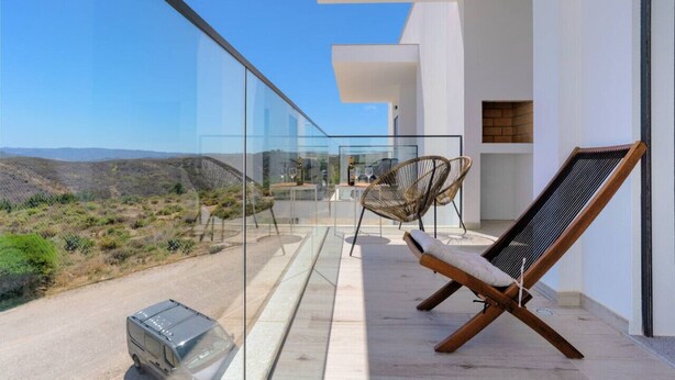 Un balcone con vista panoramica sul paesaggio, un barbecue e due sedie.
