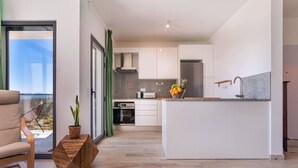 Una cucina moderna con isola centrale, mobili bianchi e vista attraverso una porta in vetro.