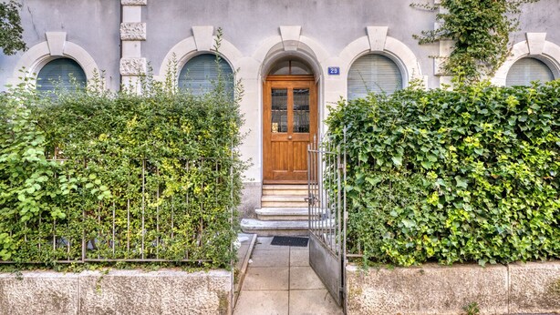 A building with a wooden door, stone steps, and a blue sign with the number 29. - Charming Breite 3 Room w/ Washer & Storage, nr Market, by Blueground (Basel)