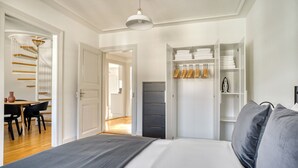 A bedroom with a bed, a wardrobe, a desk with chairs, and a staircase. - Charming Breite 3 Room w/ Washer & Storage, nr Market, by Blueground (Basel)