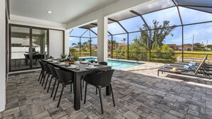 Eine Terrasse im Freien mit Esstisch, Stühlen und einem Pool.