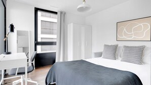 A modern bedroom with a large bed, a desk, and a wardrobe. - Luxe Opfikon 4.5 Room w/ Storage & W/D, 2 mins to Market, by Blueground (Zurich)