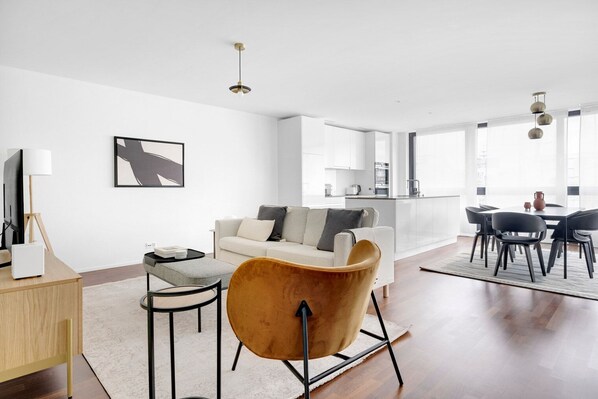 A modern living room with a sofa, a coffee table, and a dining area with chairs.