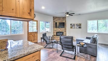 A modern kitchen with granite countertops, wooden cabinets, and a stone fireplace.