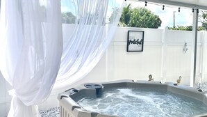 Un jacuzzi bajo un dosel blanco con una cita enmarcada en la pared.
