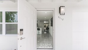 Una entrada moderna con puerta de cristal, felpudo y placa con número.