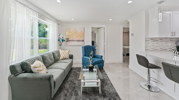 Una sala de estar moderna con un sofá gris, un sillón azul y una mesa de centro de vidrio.